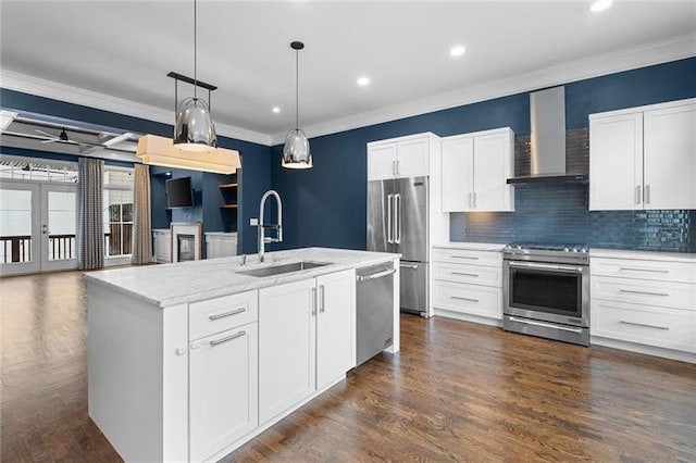 kitchen with appliances with stainless steel finishes, sink, wall chimney range hood, and white cabinets