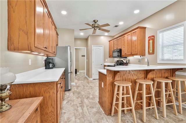 kitchen with stainless steel fridge, a breakfast bar, ceiling fan, range, and kitchen peninsula