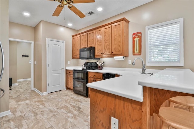 kitchen with a kitchen bar, sink, kitchen peninsula, ceiling fan, and black appliances