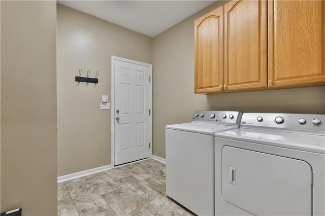 clothes washing area with separate washer and dryer and cabinets