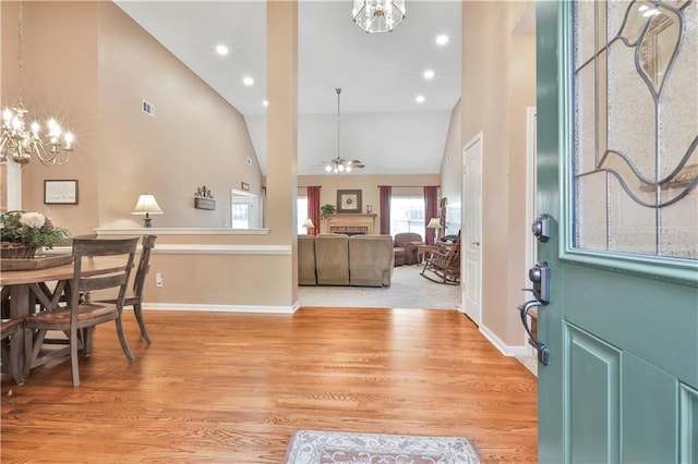 foyer featuring ceiling fan with notable chandelier, high vaulted ceiling, and light hardwood / wood-style flooring