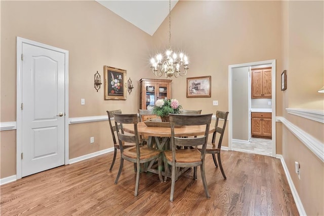 dining room with an inviting chandelier, hardwood / wood-style floors, and high vaulted ceiling