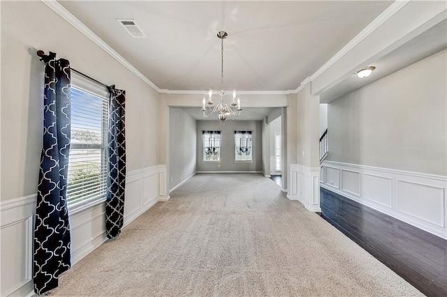 entryway featuring an inviting chandelier, ornamental molding, and carpet flooring