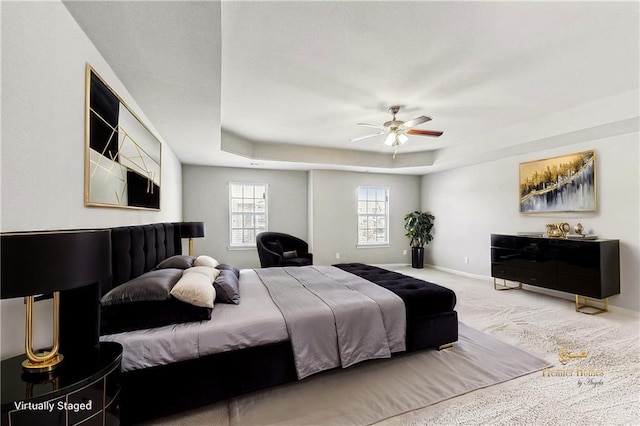 bedroom featuring a raised ceiling, ceiling fan, and carpet flooring