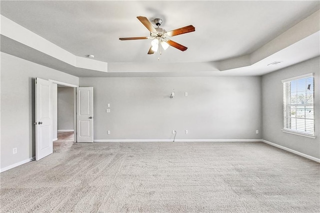 carpeted spare room with ceiling fan and a tray ceiling