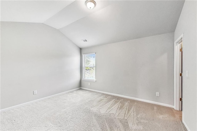 spare room with vaulted ceiling and light colored carpet