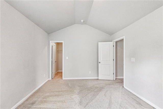 unfurnished bedroom featuring a walk in closet, lofted ceiling, light colored carpet, and a closet