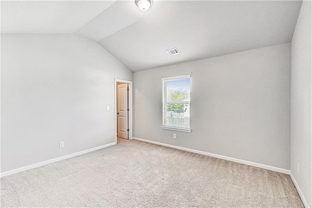 spare room featuring vaulted ceiling and light colored carpet