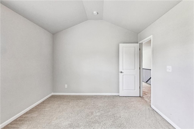 spare room with light carpet and vaulted ceiling