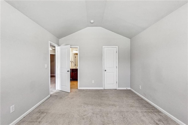 unfurnished bedroom featuring lofted ceiling, carpet flooring, and ensuite bathroom