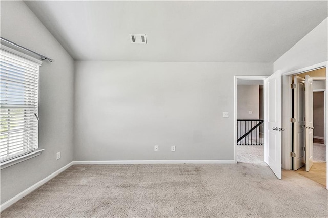 spare room with light carpet, plenty of natural light, and lofted ceiling