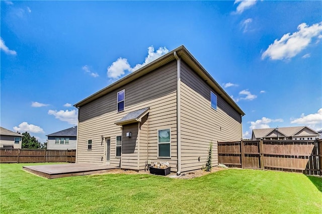 rear view of house featuring a wooden deck and a lawn