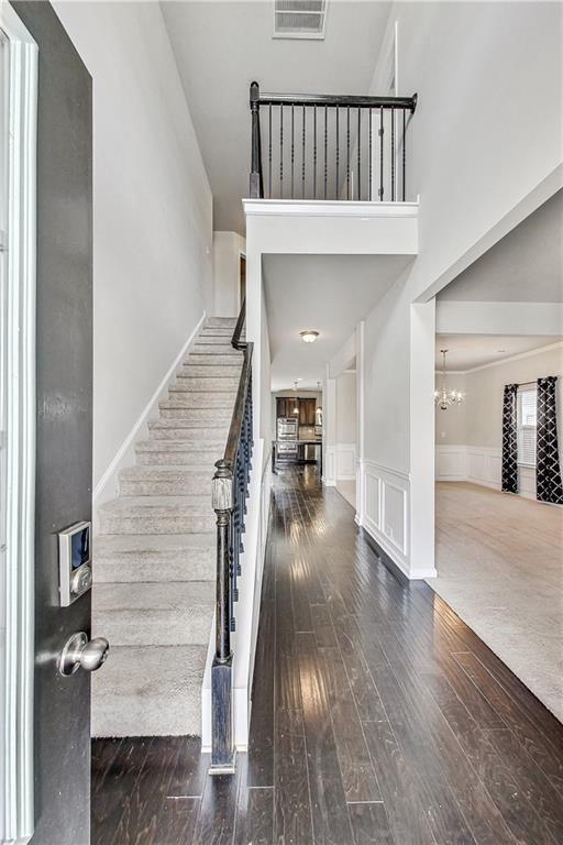 foyer featuring a towering ceiling, an inviting chandelier, and dark hardwood / wood-style flooring