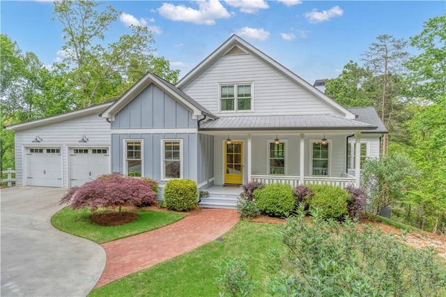 view of front of home featuring a garage, board and batten siding, a porch, a chimney, and driveway