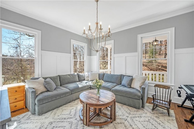 living room with a chandelier, wainscoting, wood finished floors, and a wealth of natural light