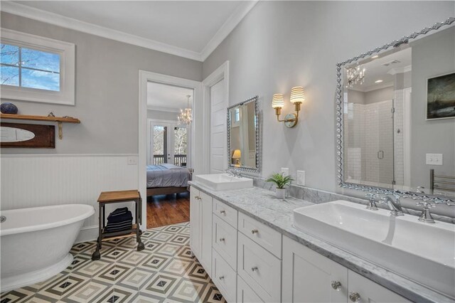 bathroom with crown molding, a sink, double vanity, a chandelier, and a stall shower