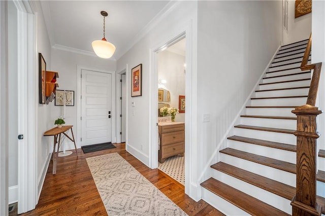 foyer with baseboards, ornamental molding, stairs, and wood finished floors
