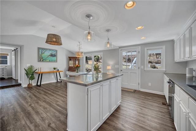 kitchen featuring white cabinetry, baseboards, dark wood finished floors, and dark countertops