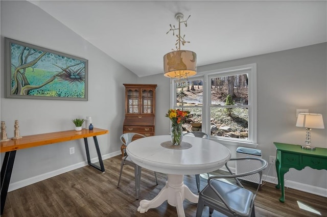 dining space featuring baseboards, vaulted ceiling, and wood finished floors