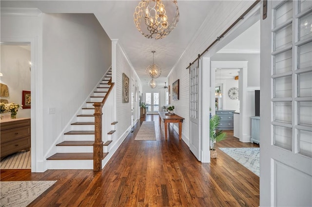 foyer entrance featuring stairway, ornamental molding, hardwood / wood-style floors, and a notable chandelier