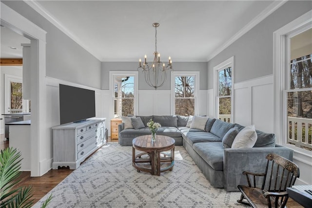 living area featuring an inviting chandelier, dark wood finished floors, a decorative wall, and wainscoting
