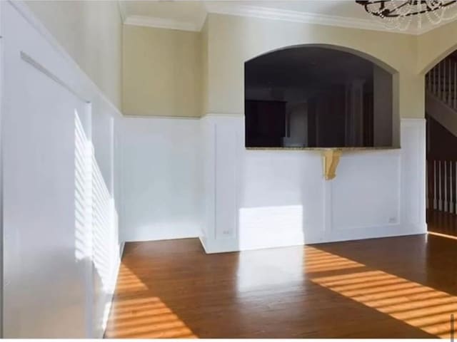 spare room featuring dark hardwood / wood-style flooring, ornamental molding, and a chandelier