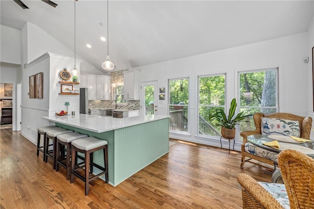 kitchen featuring light countertops, white cabinets, wood finished floors, a peninsula, and tasteful backsplash