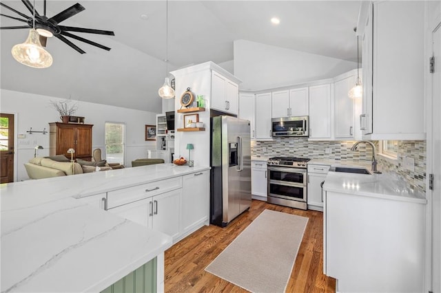 kitchen with stainless steel appliances, a sink, open floor plan, a ceiling fan, and tasteful backsplash