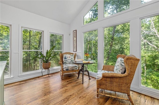 sunroom / solarium with wood finished floors, plenty of natural light, and high vaulted ceiling