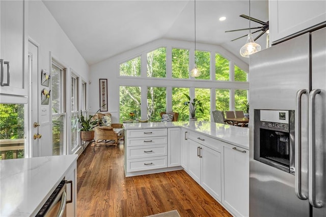 kitchen featuring stainless steel fridge, lofted ceiling, dark wood finished floors, white cabinets, and decorative light fixtures