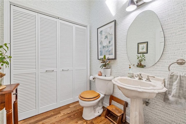 bathroom with wood finished floors, toilet, and a closet