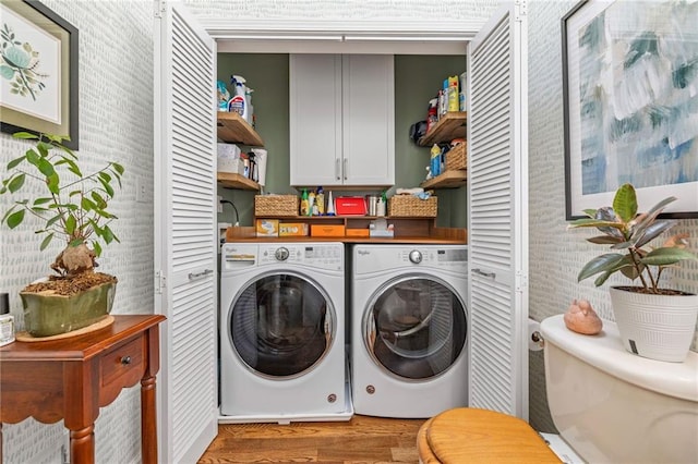 laundry room with washer and dryer, light wood-style floors, and cabinet space
