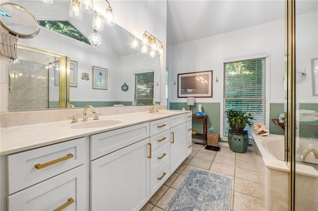 bathroom featuring lofted ceiling, wainscoting, a shower stall, double vanity, and a garden tub