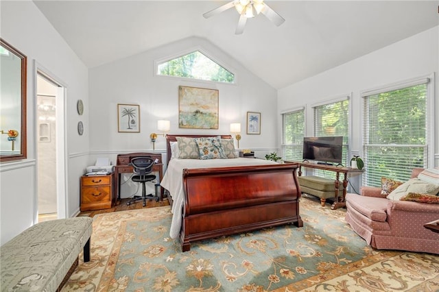bedroom featuring lofted ceiling, multiple windows, ensuite bathroom, a ceiling fan, and wainscoting