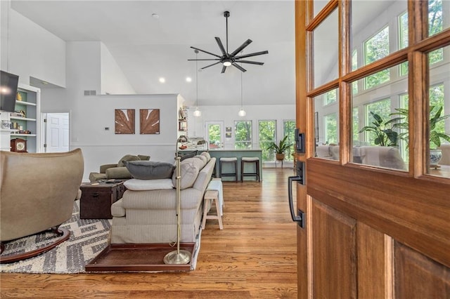 living area with high vaulted ceiling, ceiling fan, light wood-type flooring, and recessed lighting