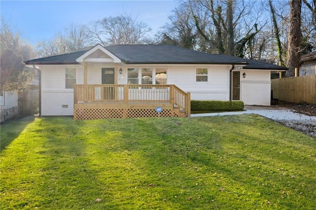 rear view of house with brick siding, a yard, and fence