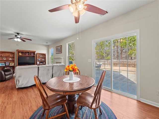 dining area with light wood-type flooring, a ceiling fan, and baseboards