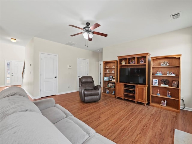 living room with a ceiling fan, visible vents, light wood-style flooring, and baseboards