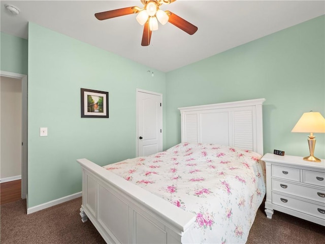 bedroom with baseboards, dark colored carpet, and a ceiling fan