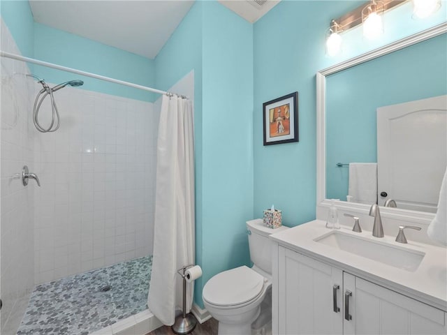 full bathroom featuring tiled shower, vanity, and toilet