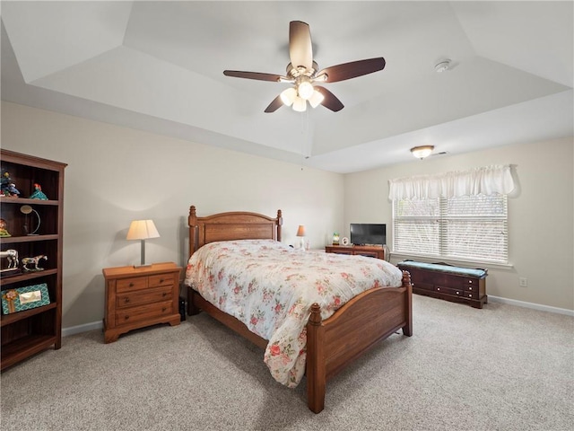 carpeted bedroom featuring vaulted ceiling, a raised ceiling, a ceiling fan, and baseboards