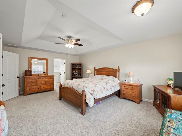 carpeted bedroom with a ceiling fan, a raised ceiling, visible vents, and baseboards