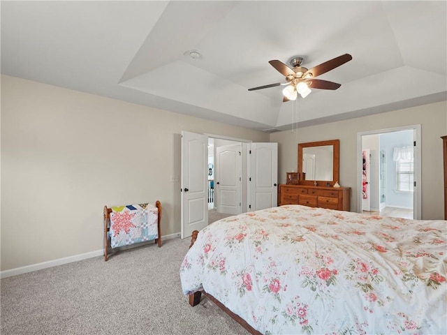 bedroom with a ceiling fan, a raised ceiling, light colored carpet, and baseboards