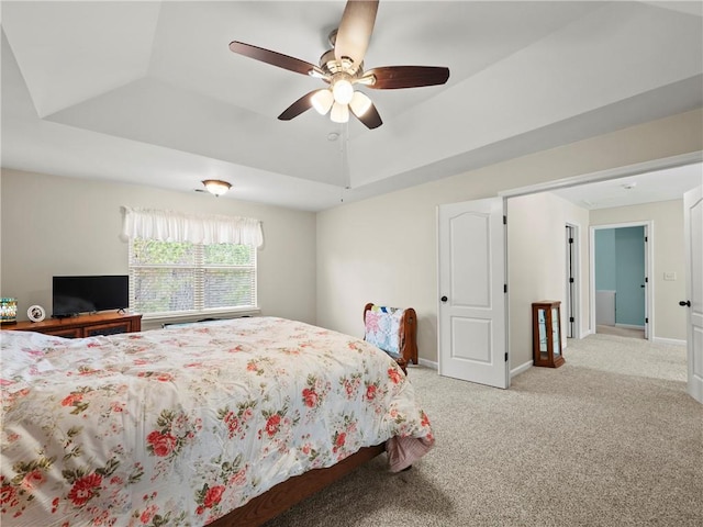 carpeted bedroom with a raised ceiling, ceiling fan, and baseboards