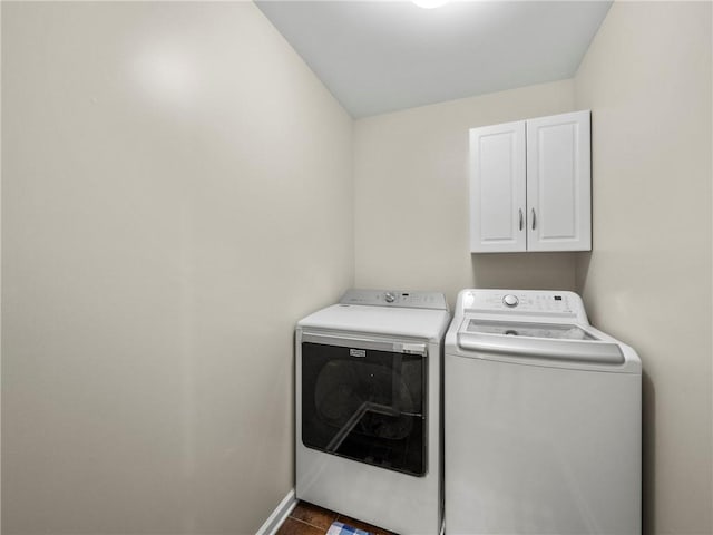 washroom featuring baseboards, cabinet space, and washing machine and clothes dryer