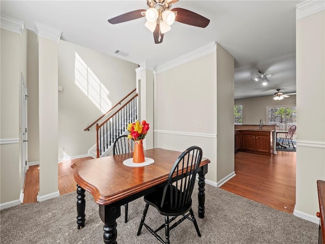 carpeted dining space featuring visible vents, wood finished floors, and ornamental molding