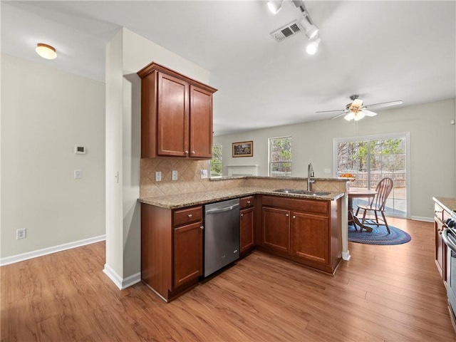 kitchen featuring a peninsula, a sink, visible vents, stainless steel dishwasher, and decorative backsplash