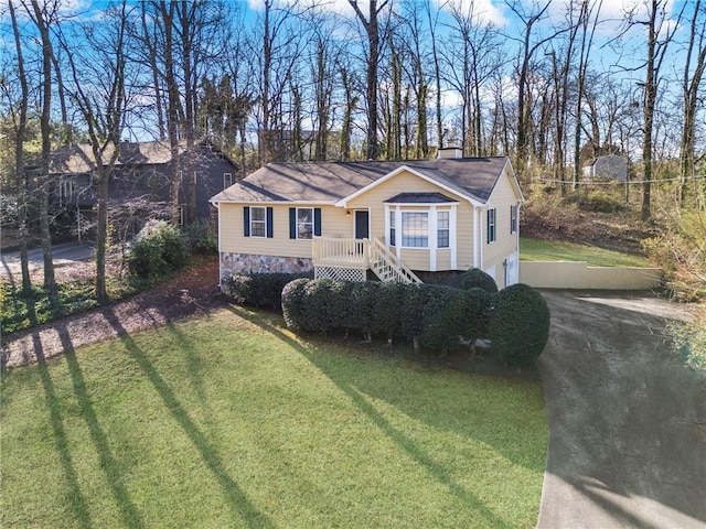 view of front of house featuring a front yard, driveway, a chimney, stone siding, and a garage