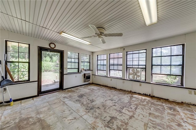 unfurnished sunroom featuring ceiling fan and heating unit