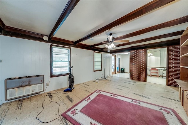 unfurnished living room with ceiling fan, beam ceiling, and heating unit